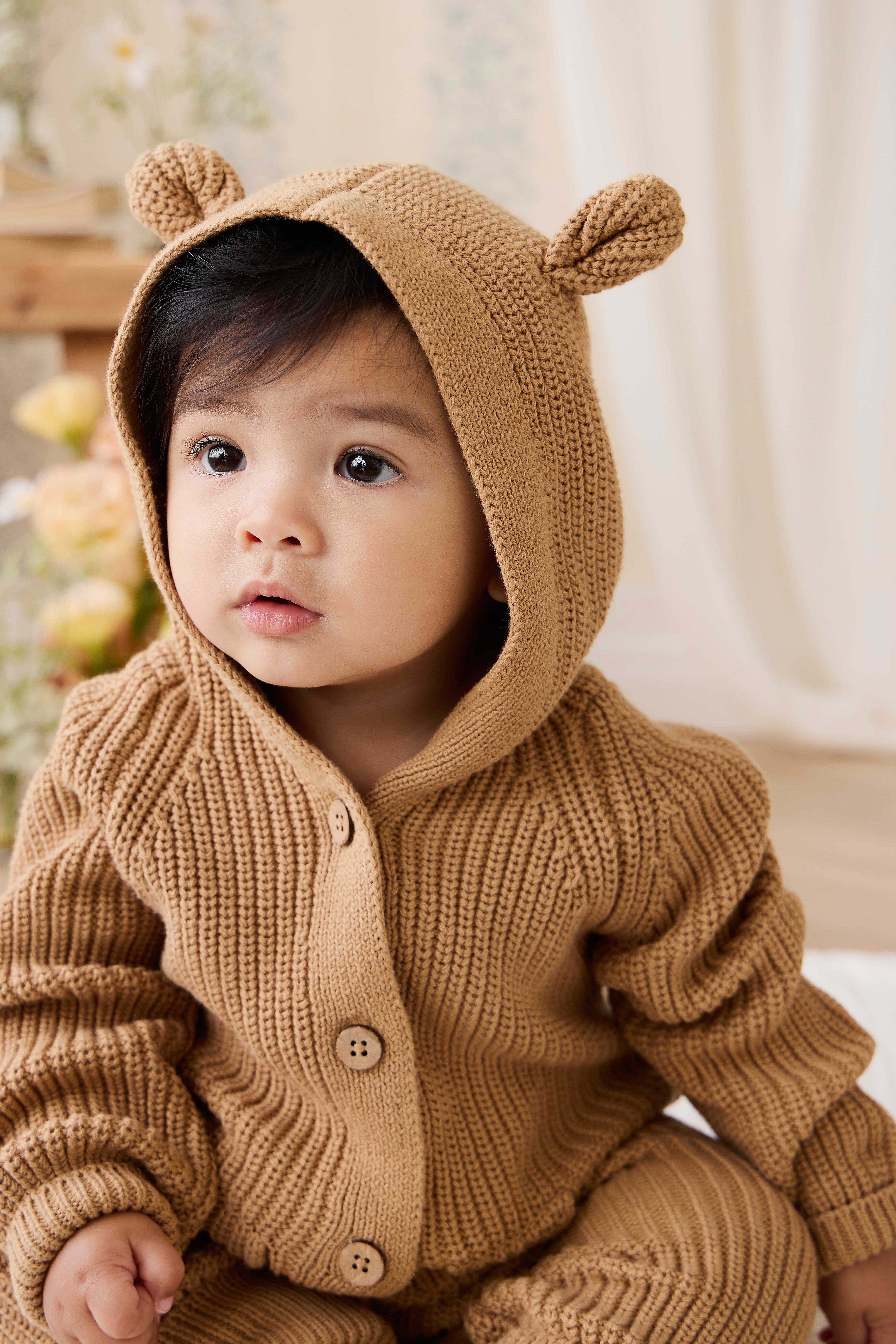 Grenouillère en tricot de coton douillet marron fauve avec capuche, oreilles et boutons sur le devant