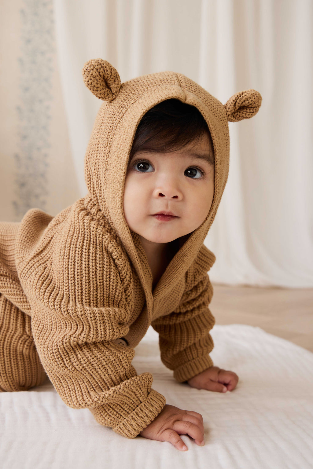 Grenouillère en tricot de coton douillet marron fauve avec capuche, oreilles et boutons sur le devant