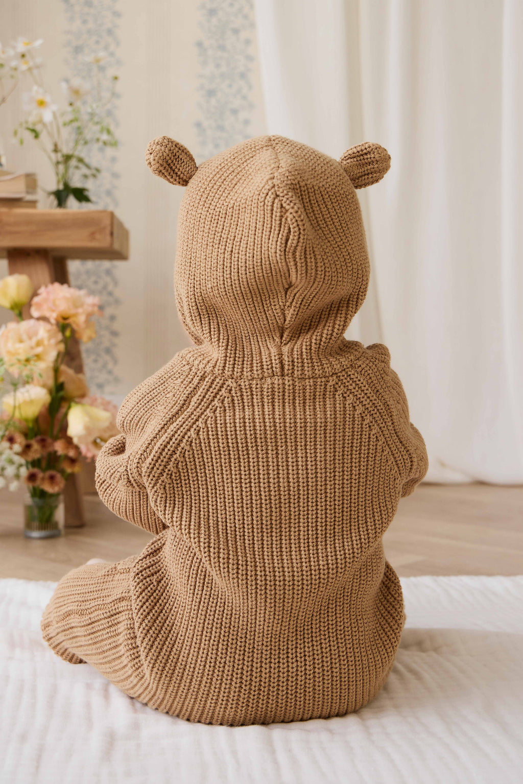 Grenouillère en tricot de coton douillet marron fauve avec capuche, oreilles et boutons sur le devant
