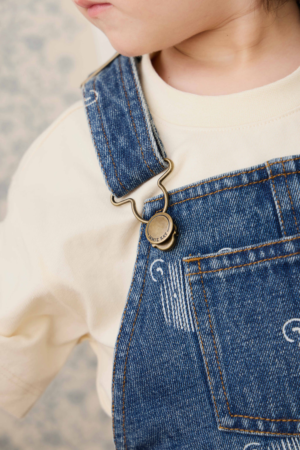 Salopette courte en jean bleu ludique avec imprimé tête d'ourson et bretelles réglables