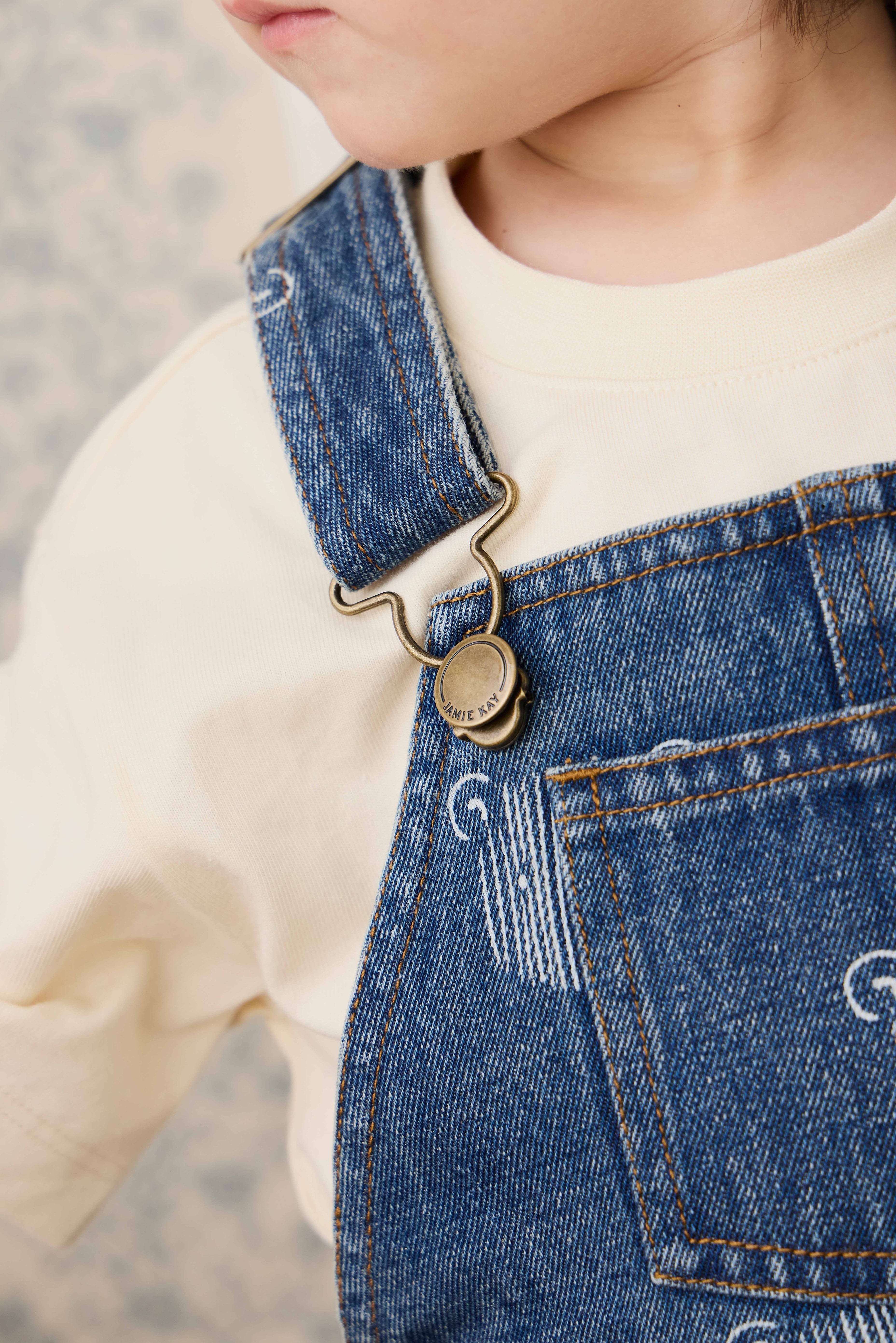 Salopette courte en jean bleu ludique avec imprimé tête d'ourson et bretelles réglables